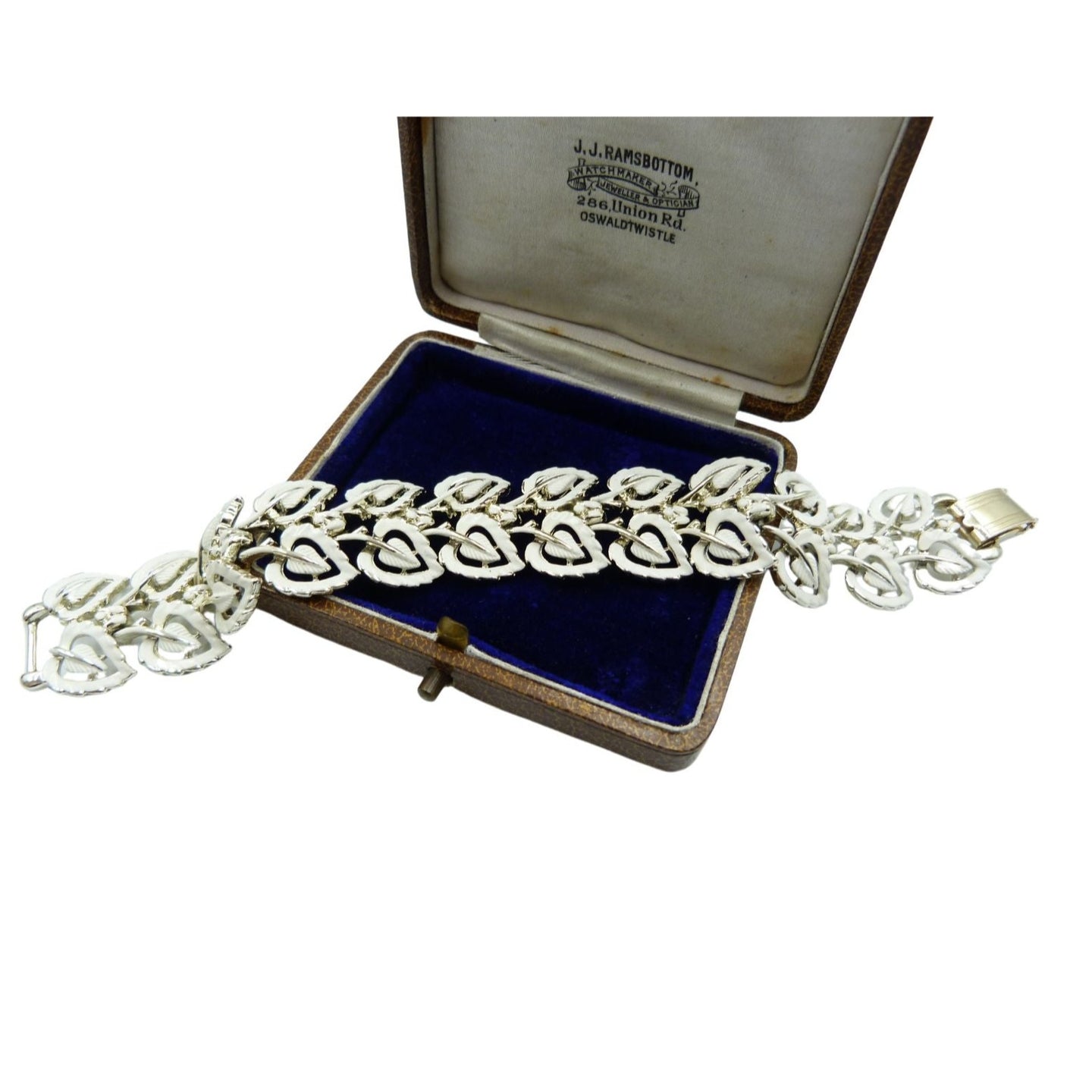 A beautiful 1950s vintage Jewelcraft bracelet made of silver tone white metal decorated with a white enamel leaf pattern design and a gold coloured clasp. 